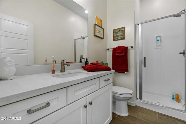 bathroom featuring hardwood / wood-style flooring, toilet, vanity, and an enclosed shower