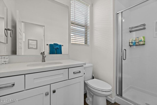 bathroom featuring toilet, a shower with door, and vanity with extensive cabinet space