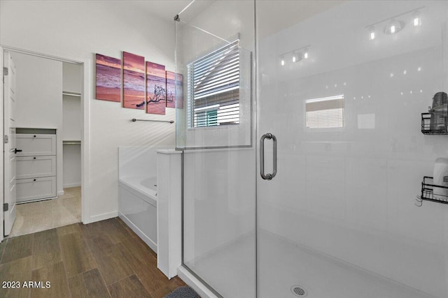 bathroom with wood-type flooring, plus walk in shower, and a wealth of natural light