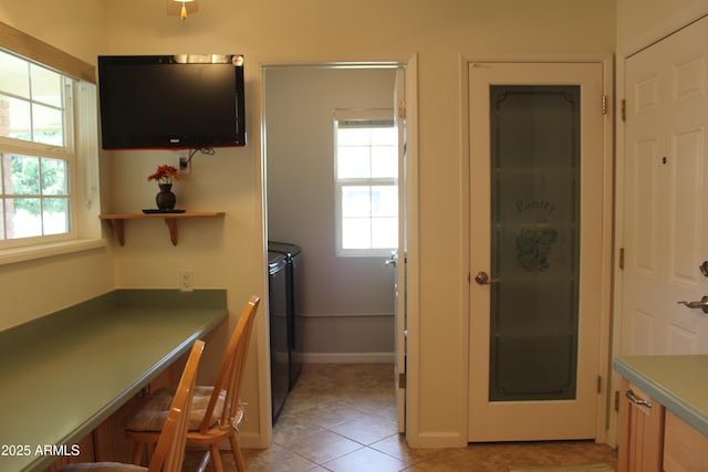 kitchen featuring a breakfast bar area, light tile patterned floors, open shelves, separate washer and dryer, and baseboards