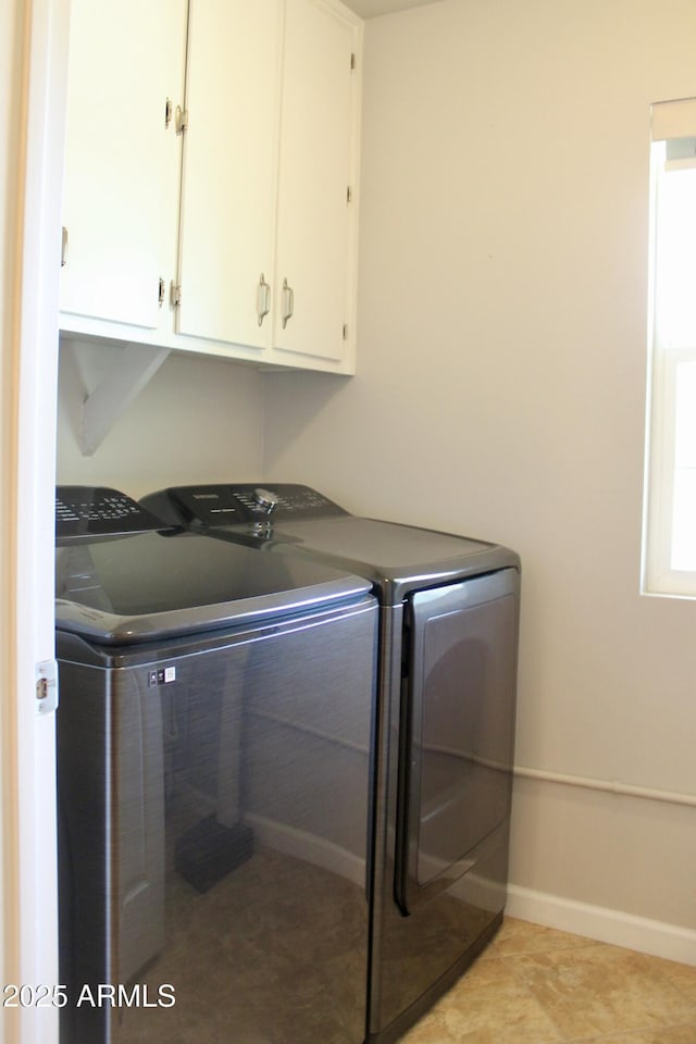 laundry room with cabinet space, light tile patterned floors, baseboards, and washer and dryer