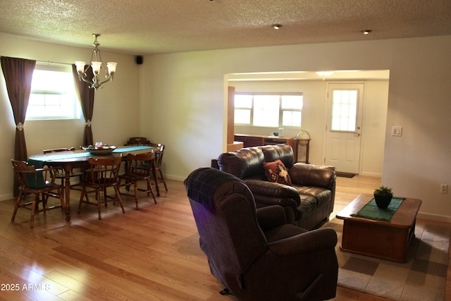 living room with light wood-style flooring, a textured ceiling, and a notable chandelier