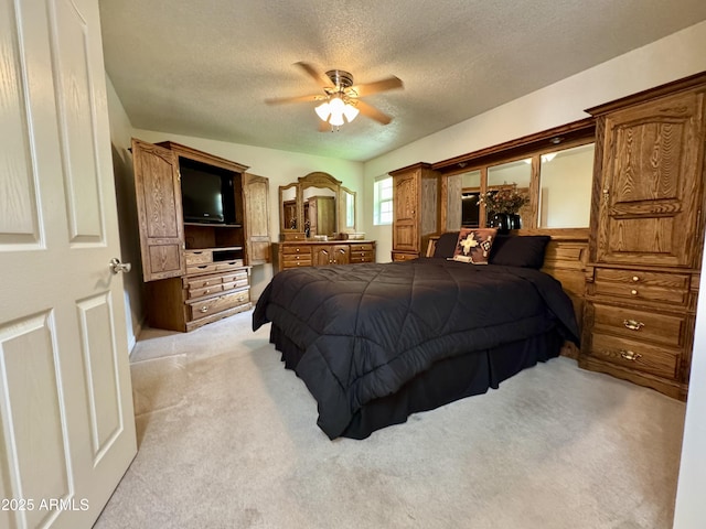 bedroom with a ceiling fan, light carpet, and a textured ceiling