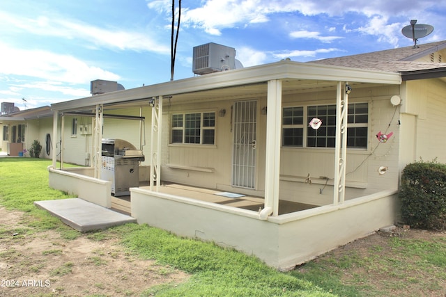 back of house featuring roof with shingles, central AC unit, and a yard