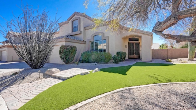 view of front of property featuring french doors, a tile roof, stucco siding, a front yard, and fence