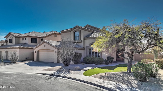 mediterranean / spanish-style house with a tile roof, stucco siding, concrete driveway, fence, and a garage