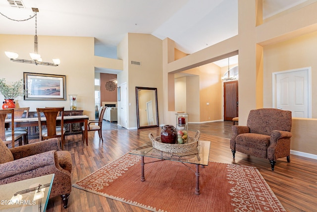 living area with visible vents, baseboards, an inviting chandelier, and wood finished floors