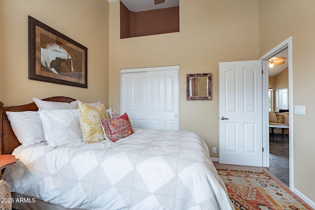 bedroom featuring a high ceiling, baseboards, and a closet