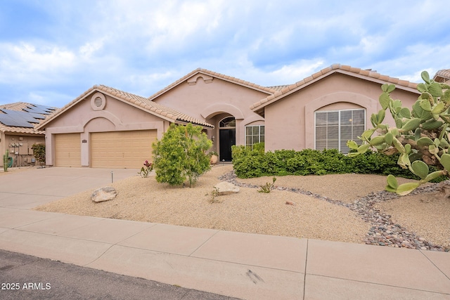 mediterranean / spanish-style house featuring a tile roof, a garage, driveway, and stucco siding