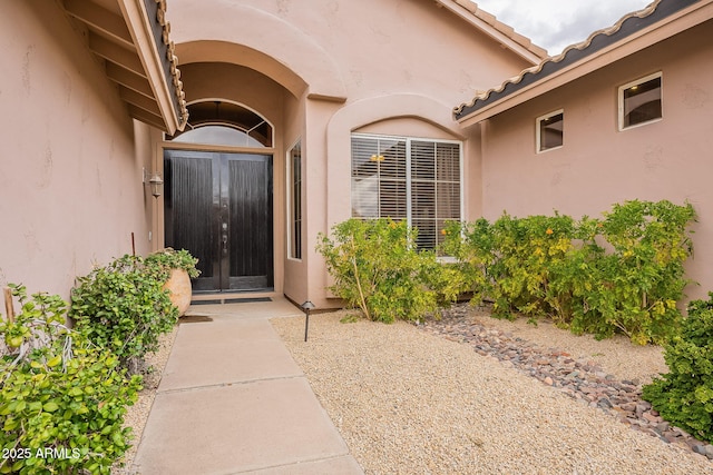 property entrance with a tile roof and stucco siding