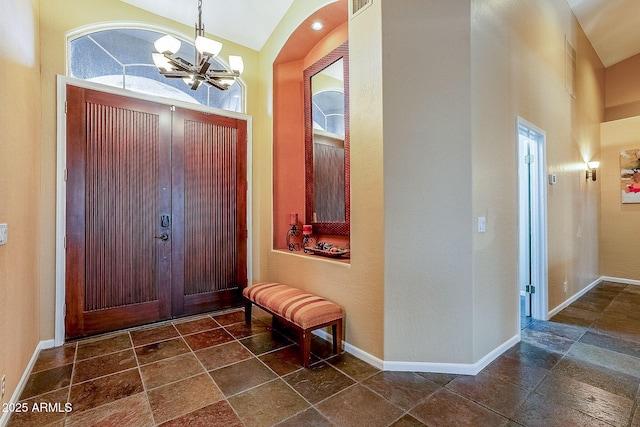 foyer entrance with stone finish floor, a notable chandelier, and baseboards