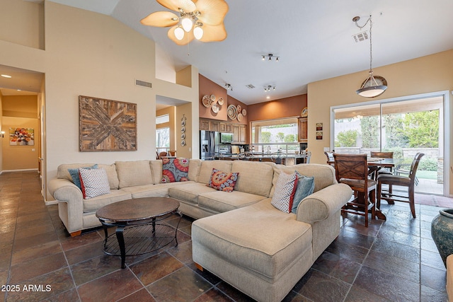 living area featuring stone tile flooring, visible vents, high vaulted ceiling, and a ceiling fan