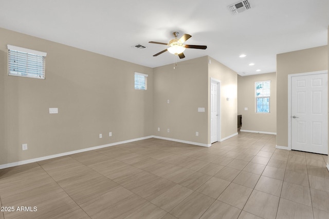 empty room with ceiling fan, visible vents, and baseboards