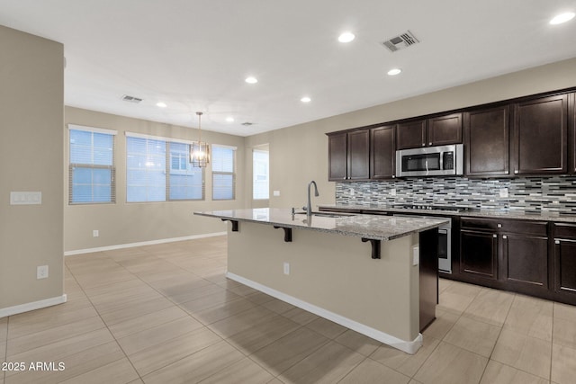 kitchen with a breakfast bar area, visible vents, stainless steel appliances, and a sink