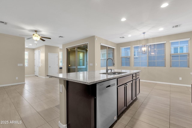 kitchen featuring light tile patterned floors, light stone counters, a kitchen island with sink, stainless steel dishwasher, and a sink