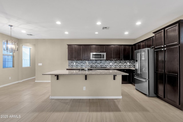 kitchen featuring a kitchen bar, appliances with stainless steel finishes, and light stone counters