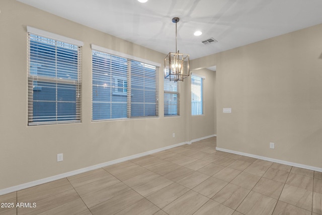 unfurnished room with a chandelier, visible vents, and baseboards