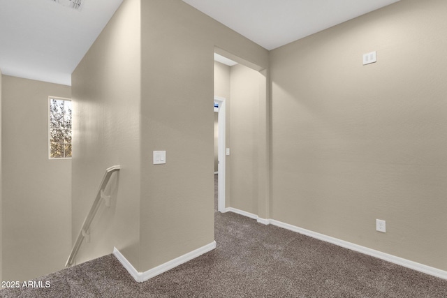 hall featuring visible vents, dark carpet, an upstairs landing, and baseboards