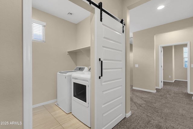 washroom with a barn door, washing machine and dryer, laundry area, visible vents, and baseboards