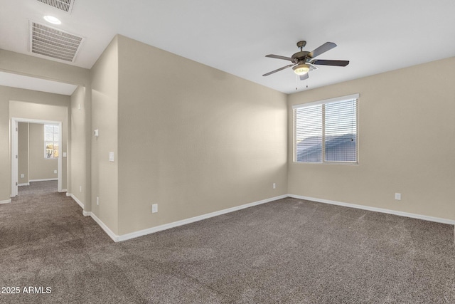 spare room featuring ceiling fan, visible vents, dark carpet, and baseboards