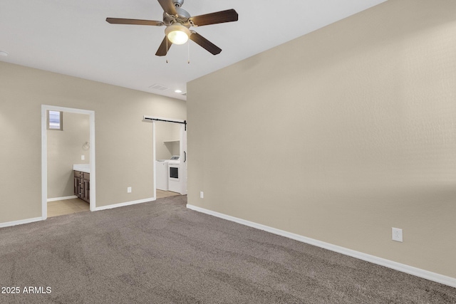 unfurnished bedroom with carpet, visible vents, a barn door, ensuite bath, and baseboards