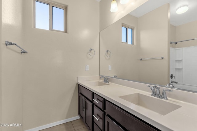 bathroom with double vanity, baseboards, a sink, and tile patterned floors