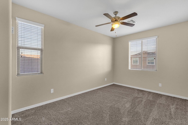 spare room featuring ceiling fan, dark carpet, visible vents, and baseboards