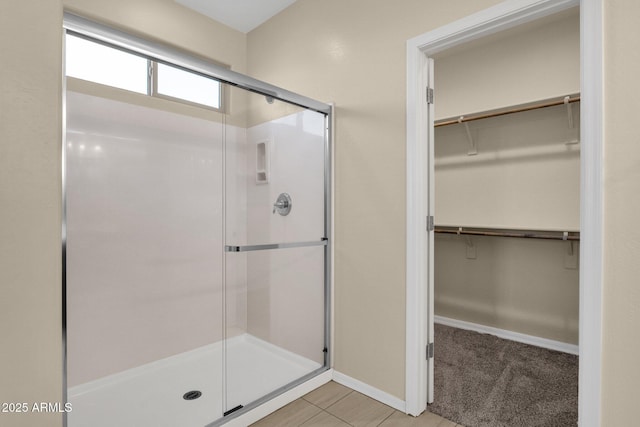 bathroom featuring a stall shower, a spacious closet, and baseboards