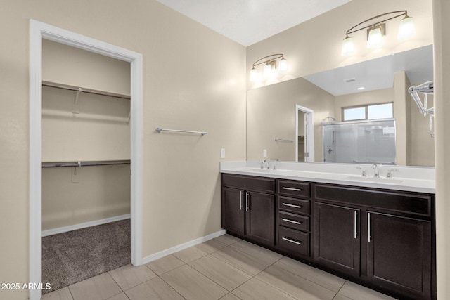 full bathroom featuring a walk in closet, a sink, a shower stall, and double vanity