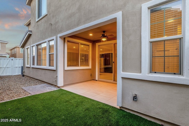 exterior space featuring a patio area, fence, a ceiling fan, and stucco siding