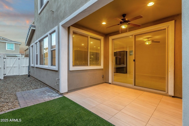 exterior space featuring a patio, stucco siding, a ceiling fan, a gate, and fence