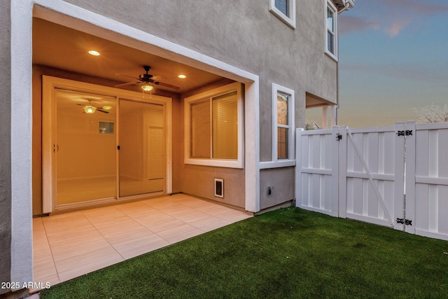 entrance to property featuring a gate, fence, and stucco siding