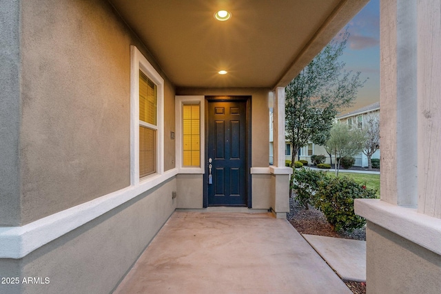 property entrance with a porch and stucco siding