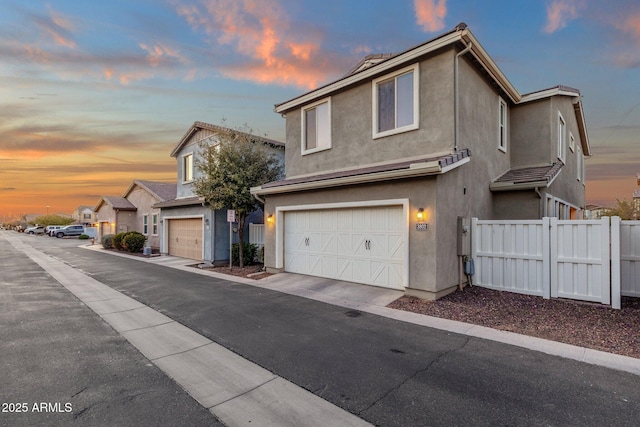 view of front of home with aphalt driveway, an attached garage, fence, and stucco siding