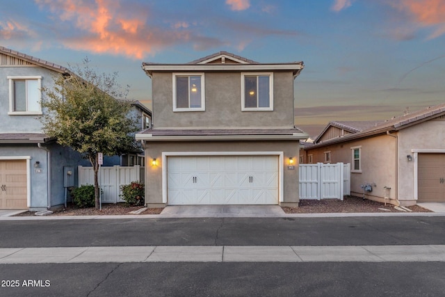 traditional home featuring an attached garage, fence, and stucco siding