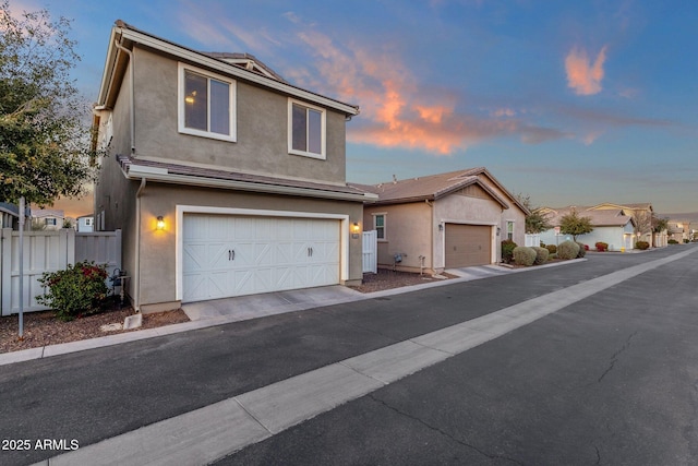 traditional-style house featuring fence, driveway, and stucco siding