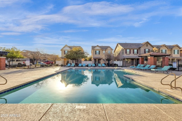 community pool featuring a residential view, fence, and a patio