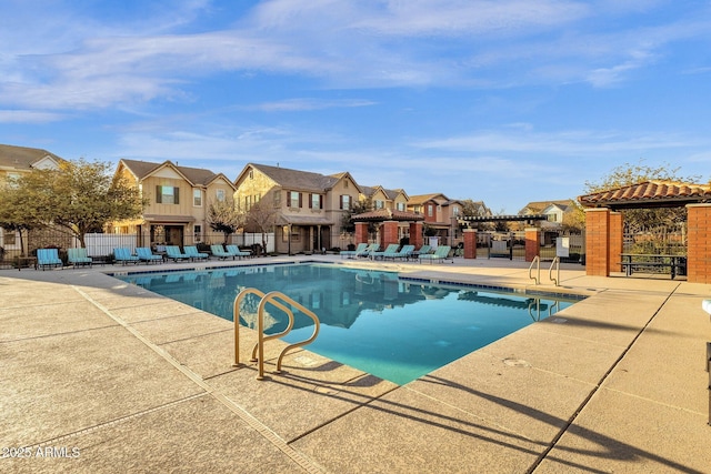 community pool featuring a patio area, fence, and a residential view