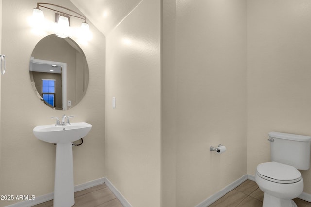 bathroom with toilet, tile patterned flooring, baseboards, and a sink