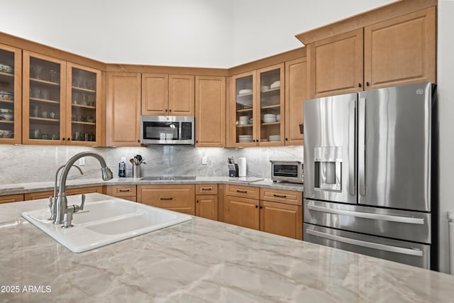 2243 E Cortez Dr, Gilbert, AZ 85234 - kitchen featuring appliances with stainless steel finishes, a sink, backsplash, light stone countertops, and glass insert cabinets