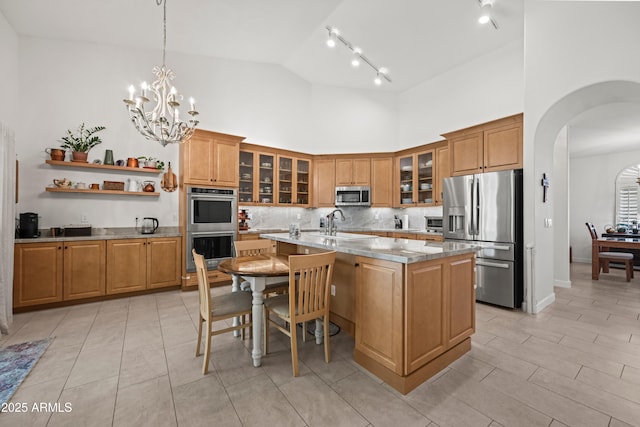 2243 E Cortez Dr, Gilbert, AZ 85234 - kitchen featuring stainless steel appliances, high vaulted ceiling, arched walkways, brown cabinets, and tasteful backsplash