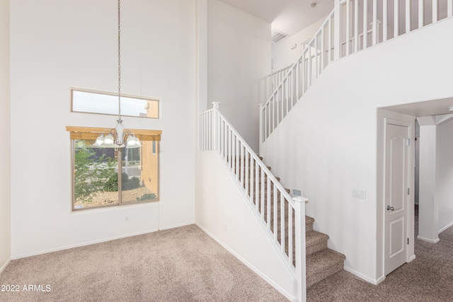 staircase with an inviting chandelier, a high ceiling, and carpet floors