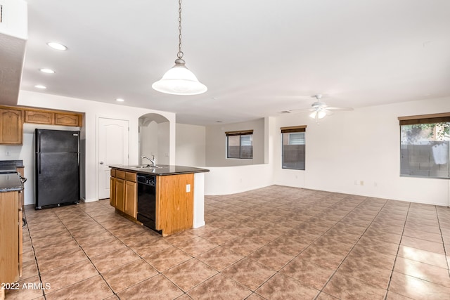 kitchen with ceiling fan, sink, decorative light fixtures, a center island with sink, and black appliances