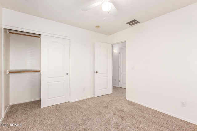 unfurnished bedroom with ceiling fan, a closet, and light carpet