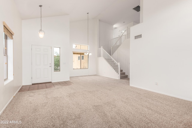 unfurnished living room featuring a healthy amount of sunlight, light carpet, and high vaulted ceiling