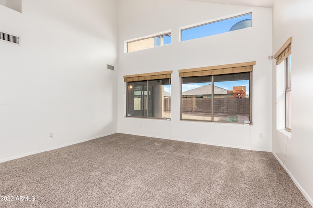 carpeted empty room with a towering ceiling and a wealth of natural light