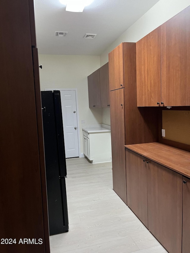 interior space with light hardwood / wood-style flooring and black fridge