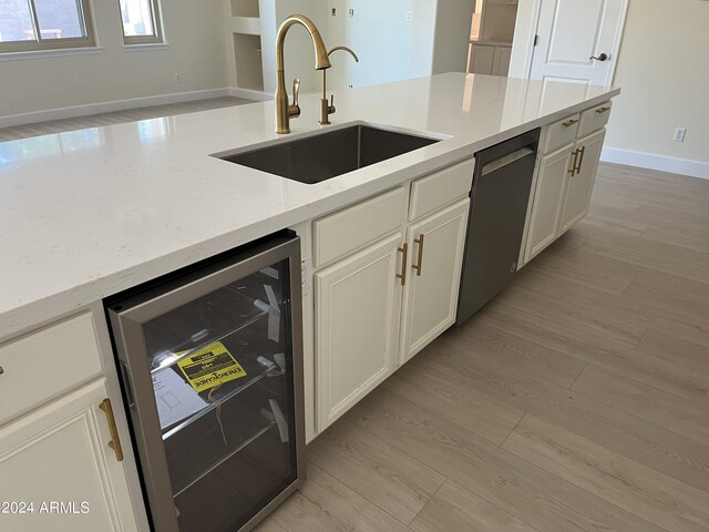 kitchen featuring dishwasher, light hardwood / wood-style floors, sink, wine cooler, and light stone countertops