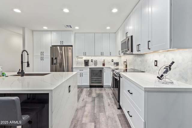 8522 E Virginia Ave, Scottsdale, AZ 85257 - kitchen with appliances with stainless steel finishes, beverage cooler, a sink, light stone countertops, and light wood-style flooring