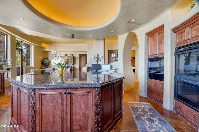 kitchen with a tray ceiling, a kitchen island, dark tile patterned floors, and black appliances